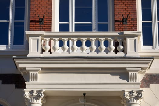 A fragment of the facade of the historic building overlooking the ornate balcony. The entire building was built of red brick and maintained in the Neo-Gothic style.