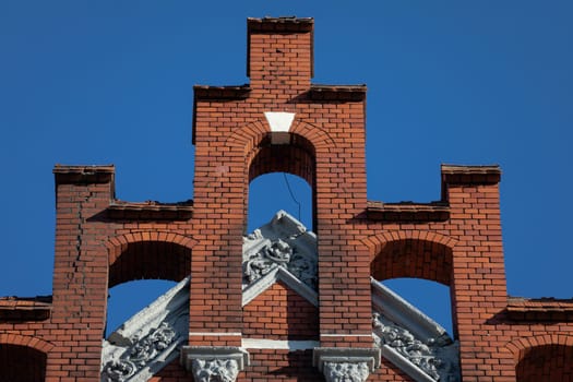 A soaring structure on top of a wall with numerous arched finials and turrets. Against the blue sky a fragment of the historic building.