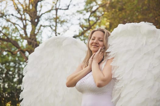 Beautiful woman dressed as an angel in the evening garden.