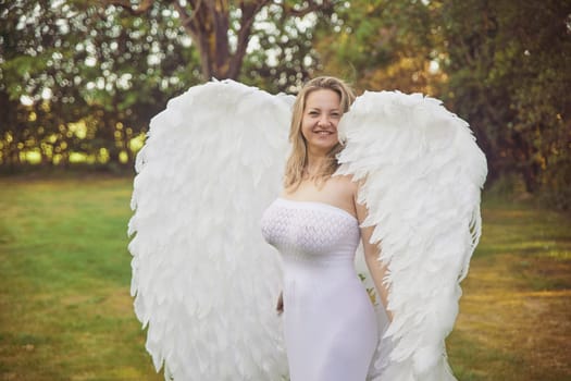 Beautiful woman dressed as an angel in the evening garden.