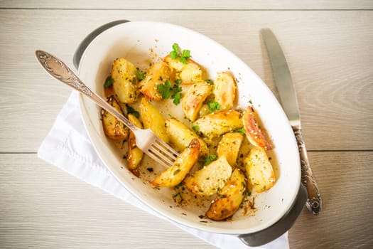 potatoes baked with sesame seeds, herbs and spices in the oven in a ceramic form.