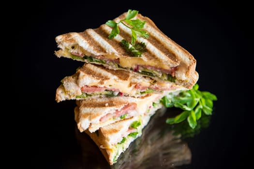 fried toasts stuffed with sausage, cheese and greens inside, isolated on black background.