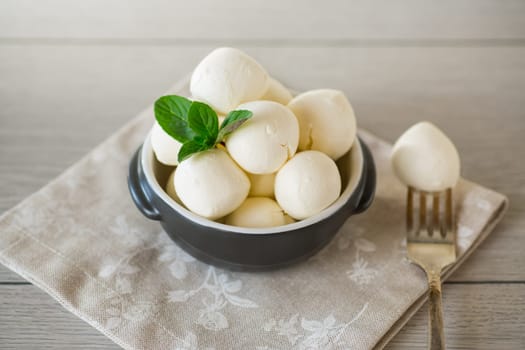 Small balls of traditional mozzarella in a ceramic bowl with mint