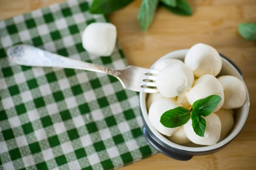 Small balls of traditional mozzarella in a ceramic bowl with mint