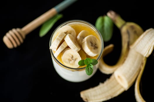 Sweet homemade yogurt with bananas and honey in a glass