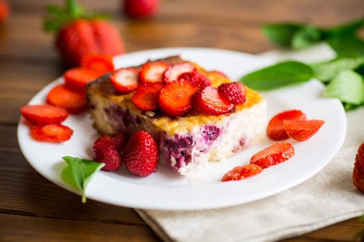 cooked cottage cheese casserole with berry and strawberry filling in a plate on the table