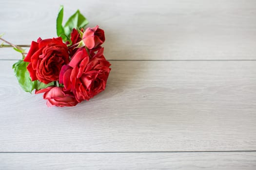 Floral background of pink, red and other roses on a light wooden table