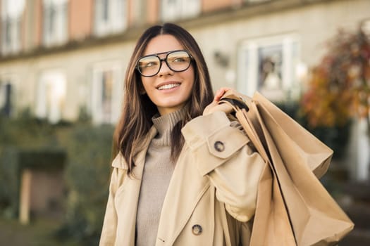 Glamorous woman in fashion glasses with shopping bags and beautiful smile in the street.