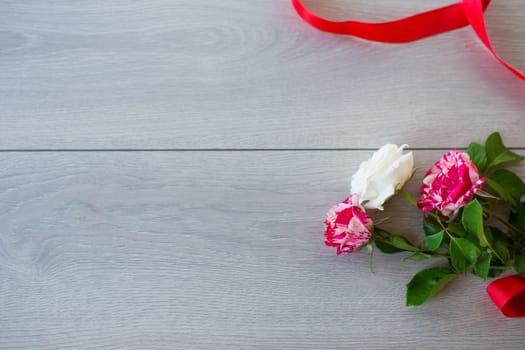 Floral background of pink, red and other roses on a light wooden table