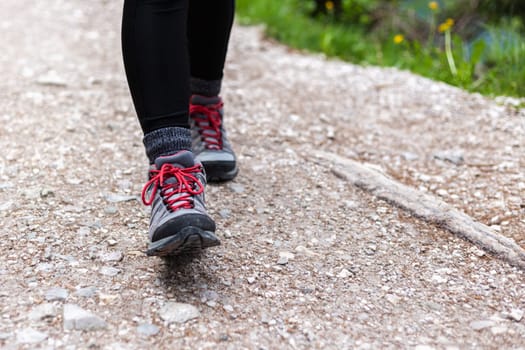 Active leisure. Close up middle-high hiking female boots on a mountains track.