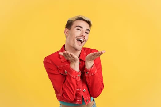 Gay man flirting while looking at camera and smiling in studio with yellow background