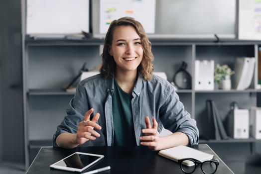 A sophisticated businesswoman is engaging in a video conference from her office or home. She's attentively looking into the web camera, articulating her thoughts and ideas with clarity and confidence