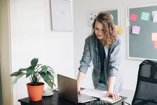 Young Professional Woman Engaged in Laptop Work at Modern Office. Student Girl Embracing Freelance Work in Business Casual Environment. Vibrant Lifestyle Concept