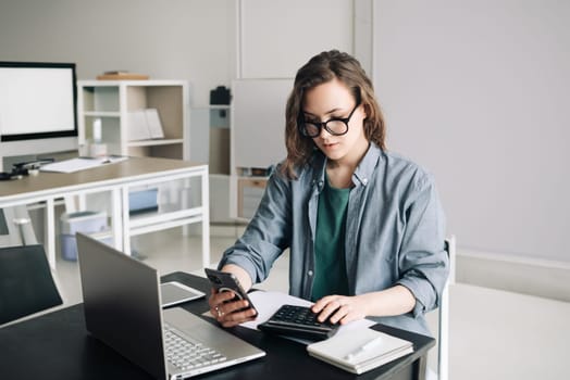 Professional Woman Accountant Managing Finances: Using Calculator and Computer in Office. Finance and Accounting Concept for Business, Financial Planning, and Money Management