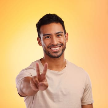 Portrait, hands and man with peace sign in studio isolated on a yellow background. Face, fashion and hand gesture, v symbol or emoji of happy young male model in stylish, designer and cool clothing