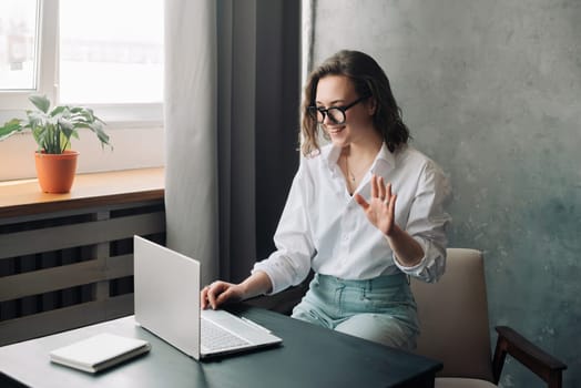 Digital Business Connection: Smiling Young Woman Leading Online Business Meeting, Embracing Remote Work as a Young Businesswoman or Freelancer Engaged in Virtual Collaboration on Laptop