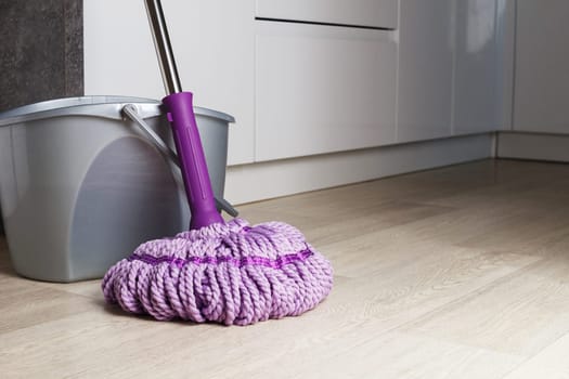 Purple mop on the bathroom floor. The concept of indoor cleaning. copy space.