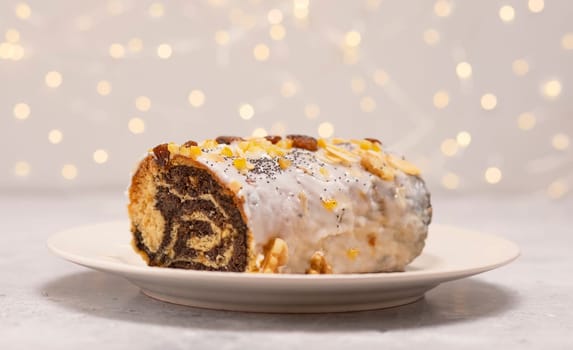 Christmas Polish strudel Makowiec with poppy seeds, traditional polish festive cake covered with sugar icing, walnuts, dried fruits on white background with lightening. Horizontal plane.Winter holiday.