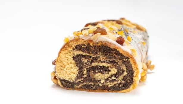 Isolated Christmas strudel Makowiec with poppy seeds, traditional polish festive cake covered with sugar icing, walnuts, dried fruits on white background. Horizontal plane