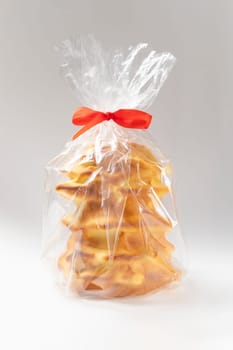 Isokated Sakotis ,sekacz, baumkuchen in transparent package. Traditional spit cake in lithuanian, polish, german, belarusian cuisine, cooked over open fire on white background Vertical plane