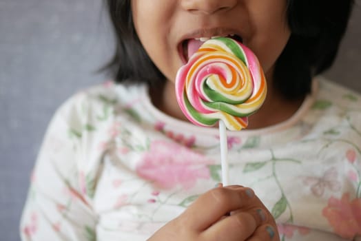 child is licking colorful candy on stick,