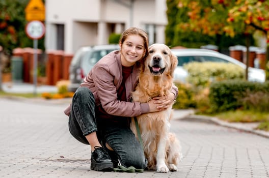 Preteen teen girl wear on golden retriever dog lace outdoors. Pretty kid child with purebred pet doggy walking at street