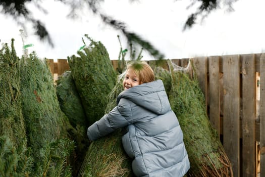 Small girl chooses a Christmas tree in the shop.