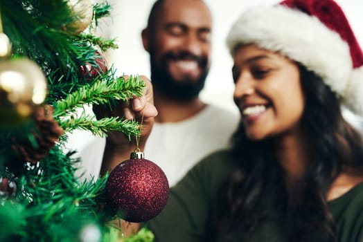 Christmas, decorating tree and happy black couple celebrate holiday season with love, happiness and festive bonding. Black woman, man smile together and enjoy decorate Christmas tree in living room.