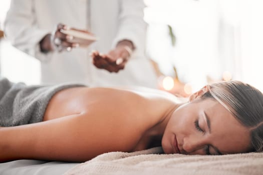 Spa, oil and woman on a table for massage, wellness and skin treatment for peace, zen and relax. Luxury, girl and masseuse with skin product for massaging, therapy and healing in a beauty salon.