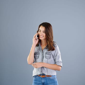 Im so glad you called. Studio shot of an attractive young woman making a phonecall against a grey background