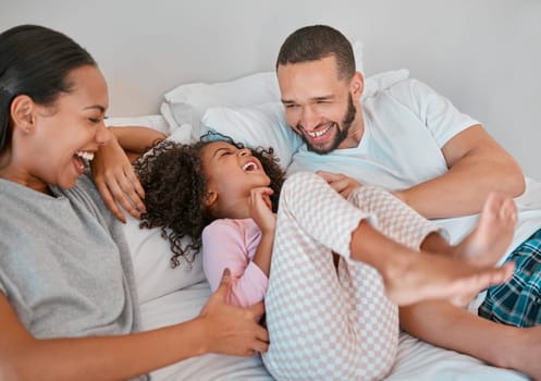 Family, parents and girl happy on bed, smile, laugh and bonding on weekend. Mom, dad or couple with kid happiness and love in pajamas, morning and being playful, care and fun together in bedroom
