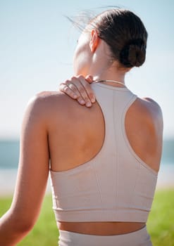 Massage, shoulder pain and fitness with woman at beach for yoga, workout and exercise training. Burnout, injury and physical therapy with girl in city park for training, sport and pilates goals.