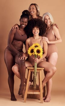 Plus size women, lingerie and group portrait with sunflower for beauty, wellness and solidarity in studio. Model team, underwear and flowers with support hug, diversity and smile by studio backdrop.