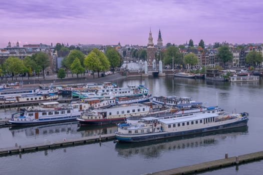 Netherlands. Evening after sunset over Amsterdam in summer. Several residential barges are moored in the harbor in the city center. Aerial View