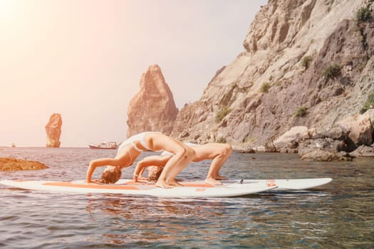 Woman sup yoga. Middle age sporty woman practising yoga pilates on paddle sup surfboard. Female stretching doing workout on sea water. Modern individual hipster outdoor summer sport activity