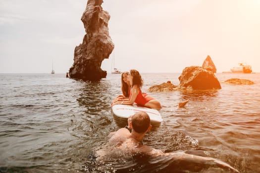 Woman sup yoga. Middle age sporty woman practising yoga pilates on paddle sup surfboard. Female stretching doing workout on sea water. Modern individual hipster outdoor summer sport activity