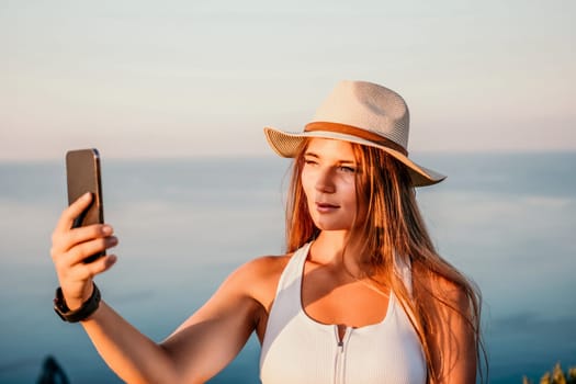 Woman travel sea. Happy tourist in hat enjoy taking picture outdoors for memories. Woman traveler posing on the beach at sea surrounded by volcanic mountains, sharing travel adventure journey