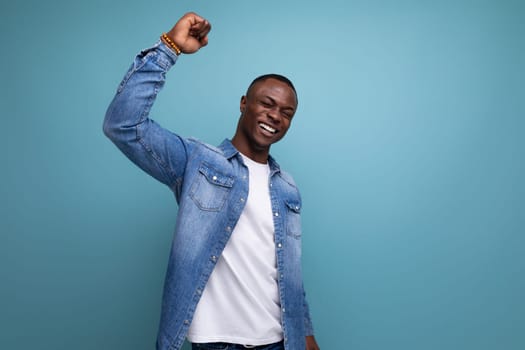 kind friendly young american man in denim clothes on blue background with copy space.