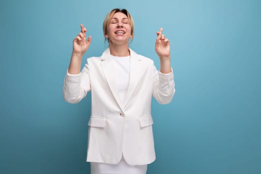 young blond business woman in a white elegant jacket and skirt crossed her fingers.