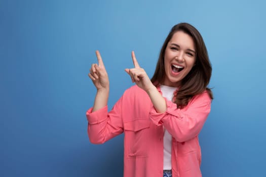 positive emotional black-haired woman in casual style announces discounts on studio background.