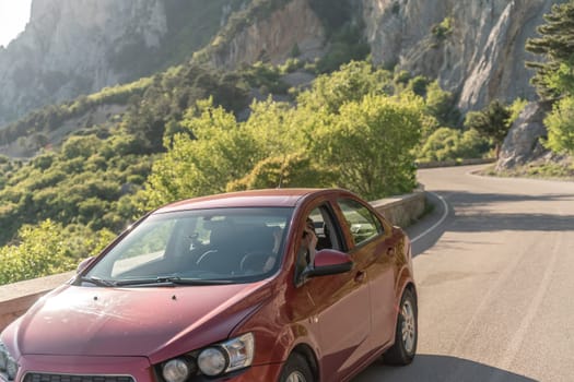 Woman driving a car. A lady in sunglasses takes the wheel of her new car. Rides along the road against the backdrop of mountains and the sea