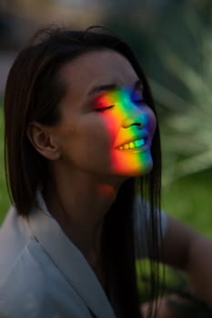 Portrait of caucasian woman with rainbow beam on her face outdoors