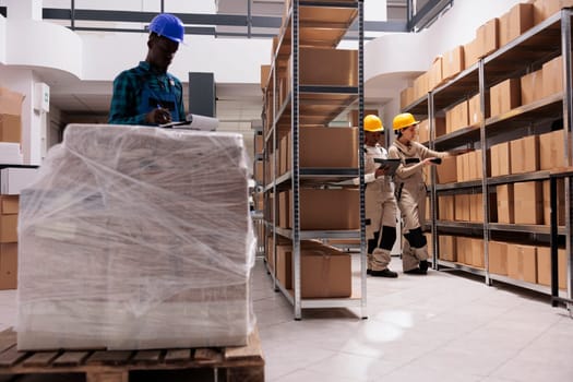 Delivery service storage workers managing parcel receiving and scanning boxes. Caucasian and african american warehouse colleagues using barcode scanner and checking freight documents before shipping
