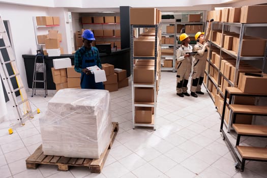 Industrial warehouse coworkers doing freight inventory, managing big parcel delivery. Storehouse employees making cargo transportation registration and scanning cardboard boxes barcodes