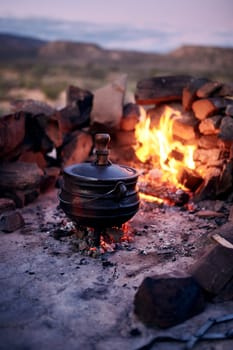 Cook it low, cook it slow. a traditional South African food being cooked by campfire outdoors