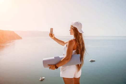 Young woman with black hair, fitness instructor in pink sports leggings and tops, doing pilates on yoga mat with magic pilates ring by the sea on the beach. Female fitness daily yoga concept