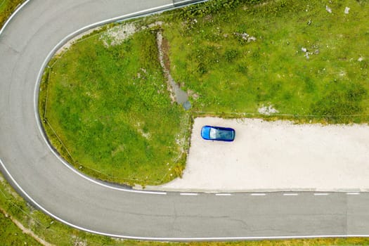 Top view on the blue car stands at the exit by the road near the Giau pass.