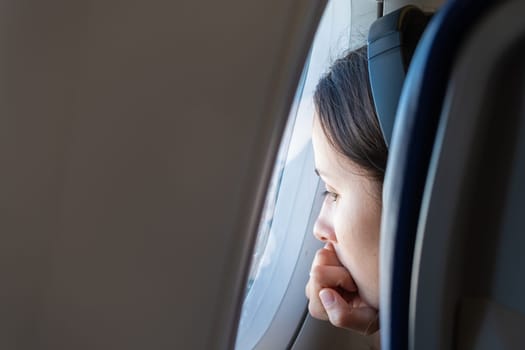 Young woman in headphones looks out the window of the plane, January 2023, Rome, Italy