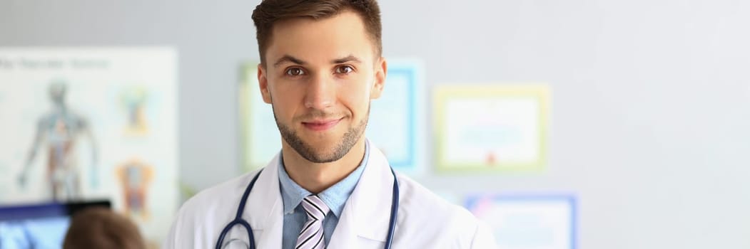 Friendly male general practitioner standing in office. Medical care and doctor appointment or insurance concept