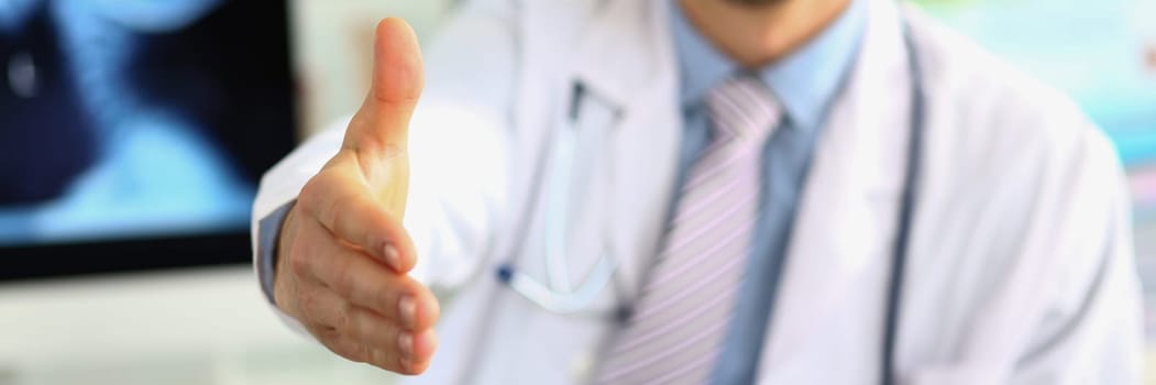 Closeup of male doctor offering handshake in office. Welcome gesture and health insurance concept